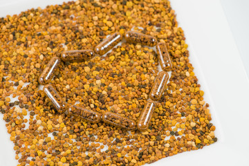 Heart of homeopathic pills with bee pollen on a white plate (sha