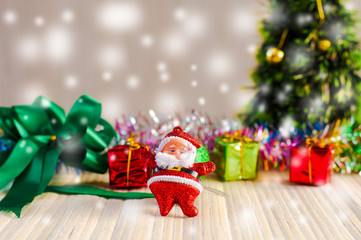 Santa Claus doll against a Christmas tree with gift box on wood