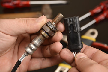 mechanic shows oxygen sensor  and connector