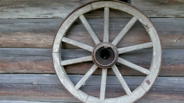 The round wheel hanging on the wall of the house. It serves as the decoration outside the log house