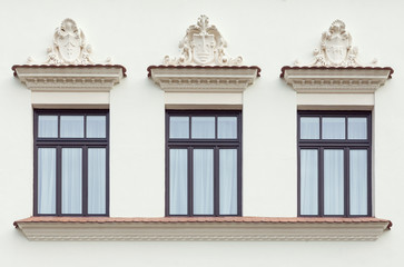 Palace facade and three windows decorated with classic style stone ornaments