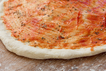 Cooking of the pizza dough, covered with sauce and seasonings