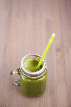 A green smoothie in a mason jar with tube