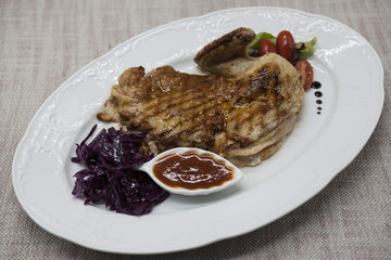 Juicy roast chicken with vegetables and ketchup. Served on porcelain plate on a tablecloth. Fried chicken tapaka, tobacco.