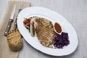Juicy roast chicken with vegetables and ketchup. Served on porcelain plate on a tablecloth with fork and knife . Fried chicken tapaka, tobacco.