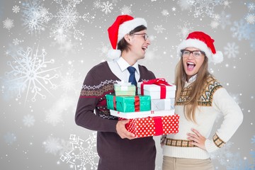Composite image of geeky hipster couple holding presents 
