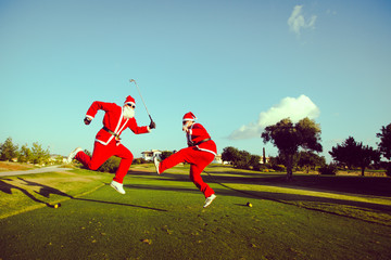 Two Santa Claus jumping on a golf course