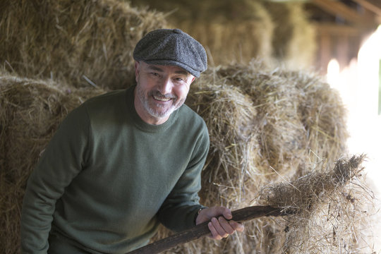 Happy man cleaning the stables