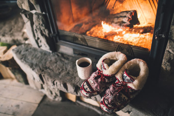 Christmas comfortable slippers by the warm cozy fireplace. Relaxing atmosphere in a chalet by...