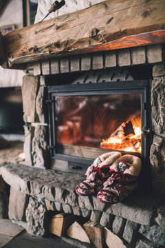 Christmas comfortable slippers by the warm cozy fireplace. Relaxing atmosphere in a chalet by authentic vintage fireside. Winter and Christmas holidays concept