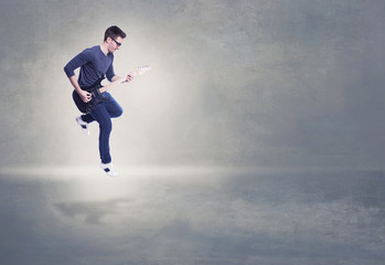 Fototapeta na wymiar Addicted to music. Young man playing electric guitar jumping on background