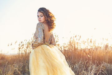 Cute lady walking through the field. Sunset background