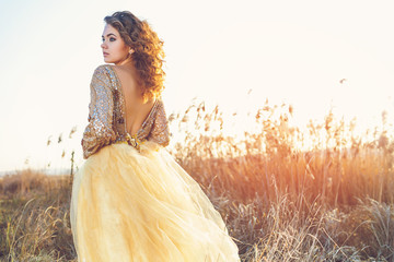 Cute lady walking through the field. Sunset background