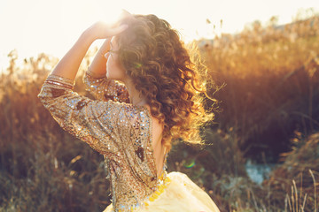 Cute lady walking through the field. Sunset background