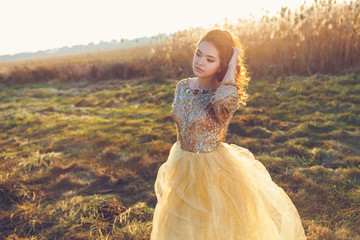 Cute lady walking through the field. Sunset background