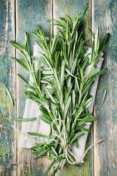 Bunch of rosemary on wooden table, rustic style, fresh organic herbs, top view