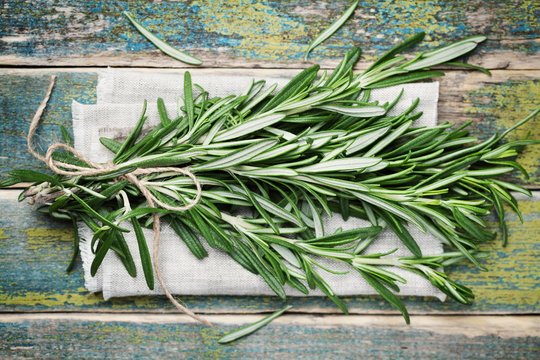 Bunch of rosemary on wooden table, rustic style, fresh organic herbs, top view
