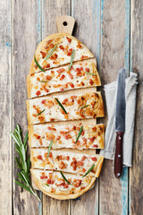 Tart Flambe or Flammkuchen on wooden cutting board, traditional Alsatian pie, rustic style, top view