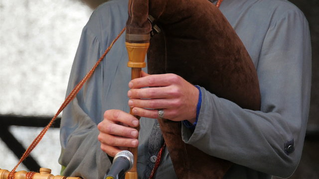 A man playing a flute on the stage with the microphone infront of him