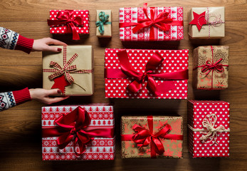 Woman organising beautifuly wrapped vintage christmas presents on wooden background, view from above