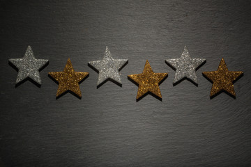 Fototapeta na wymiar Reihe aus silbern und golden Sternen auf Schiefer Untergrund