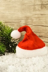 Obraz na płótnie Canvas Eine Weihnachtsmannmütze im Schnee liegend mit Tannenzweig daneben
