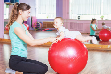 Mother with happy baby doing exercises with gymnastic ball © petunyia