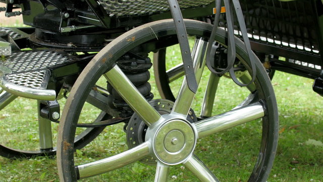 The metal wheels of the carriage in the grass. This the modern carriage being handled by the horses in Tartu