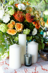 The big white candles on flowers background. A wedding composition, an ornament