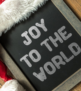 Joy to the World written on blackboard with santa hat