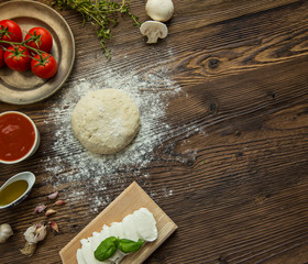 Italian pizza preparation with ingredients around.