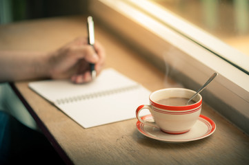 writing on notebook with coffee cup