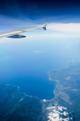 Fototapeta na wymiar land and ocean bird's eye view shot with plane wing