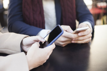 Couple looking at their smart-phones while sitting in terrace bar