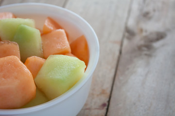 closeup melon slice in white dish with wood table background