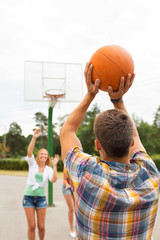 group of happy teenagers playing basketball