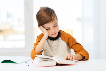 student boy reading book or textbook at home