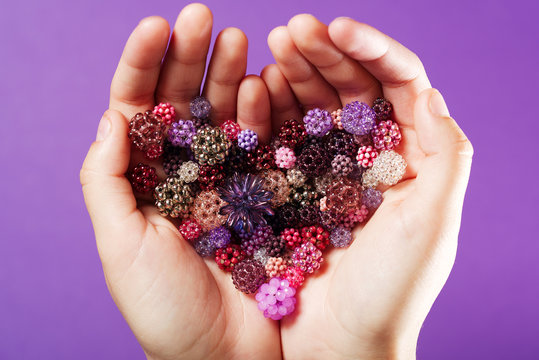 Hands with hand-woven beads in the shape of heart