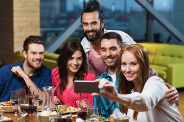 friends taking selfie by smartphone at restaurant