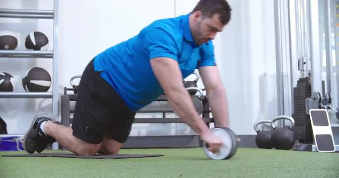 Man working out with an ab roller at a gym