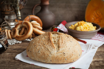 Russian rustic still life: a samovar with bagels and homemade bread with flax seeds. Selective focus. Toned