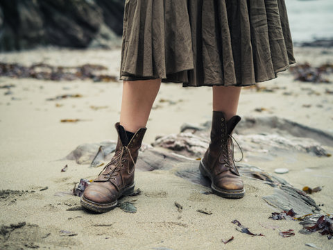 Feet of young woman wearing boots on beach