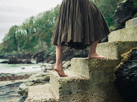 Barefoot woman walking up steps in nature