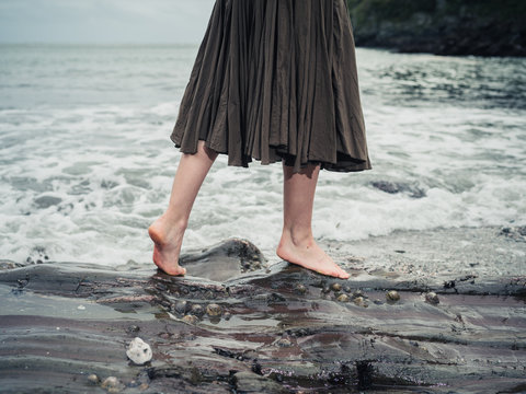 Feet of young woman walking on rocks in water