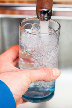 Filling up a glass with drinking water from kitchen tap