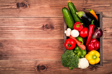 Fresh vegetables in the wooden box on the rustic background.