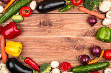 Fresh vegetables on the wooden background as frame for text.