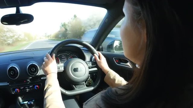 Young woman driving in a car, over shoulder view