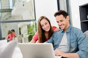 cheerful young couple man and woman in sofa at home with laptop computer