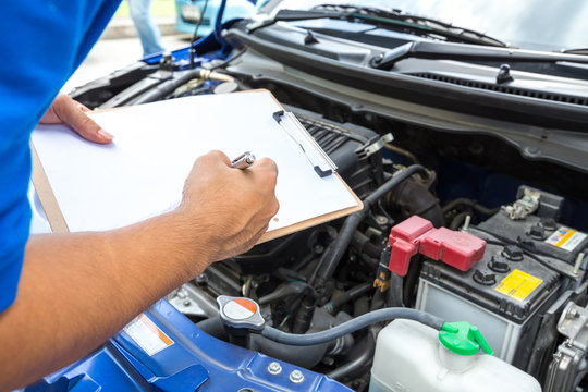 Fototapeta Mechanic man holding clipboard and check the car